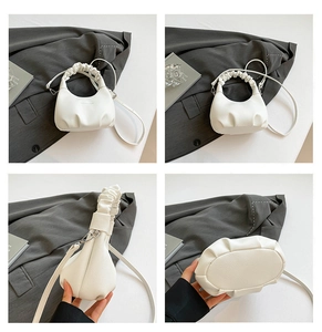 Macro details of white pleated cloud bag with litchi texture and adjustable strap