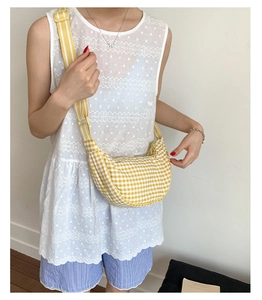 Detailed close-up of yellow gingham crescent bag with wide striped shoulder strap