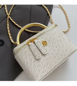Detail of ostrich texture leather handbag with gold metal handle and floral emblem