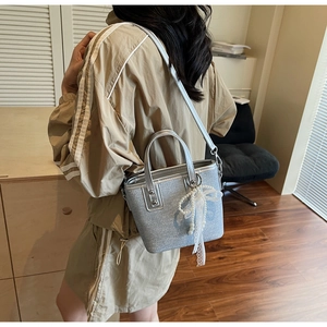 Detailansicht einer silbernen Eimertasche mit Perlenspitze und metallischem Griffdesign