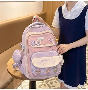 Detail of purple student backpack featuring Monday Lucy logo and plush rabbit accessories
