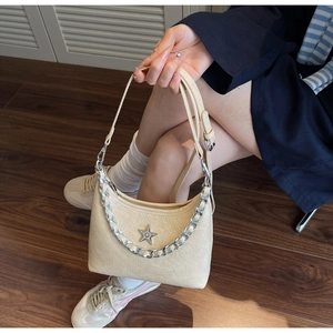 Détail d'un sac bandoulière beige en demi-lune avec logo étoile brillante et chaîne argent