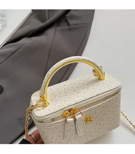 Detail of ostrich embossed white box bag with gold floral zipper and metal handle