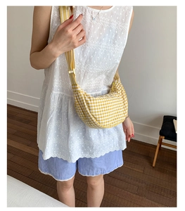 Detail of yellow checkered dumpling bag with adjustable strap worn as a crossbody bag