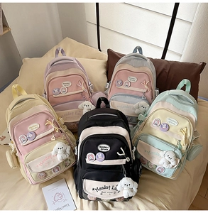 Detail of pastel student backpack with cute pins and plush puppy pendant on bed