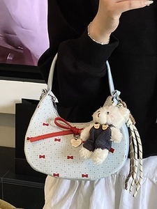 Blue polka dot crescent bag with red bows and plush bear charm for fashion-forward women