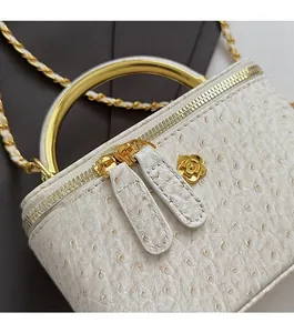 Macro view of cream ostrich pattern leather handbag with gold floral zipper details