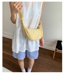 Chic yellow gingham dumpling crossbody bag shown on model for a trendy casual style