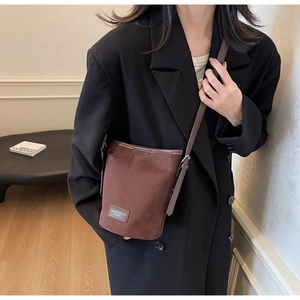 Detailaufnahme der braunen Bucket-Bag mit Markenetikett und langem Schultergurt