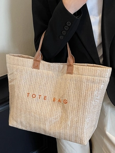 Large woven tote bag with orange text and brown leather handles for summer fashion