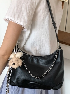 Fashionable black faux leather tote bag with silver chain and cute dog charm on shoulder