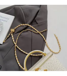 Detail of white ostrich texture bag featuring golden curved handle and metal chain strap