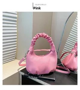 Detail of pink pleated leather handbag featuring adjustable strap and metallic hardware
