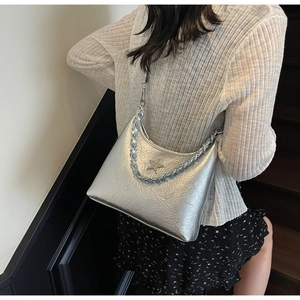 Détail d'un sac à épaule argenté métallisé avec étoile sur l'épaule d'une femme