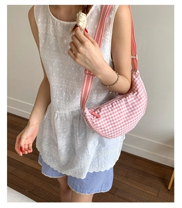 Detailed view of pink plaid dumpling bag with adjustable striped strap on a model