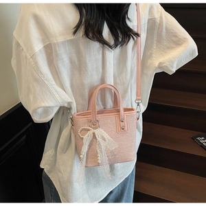 Detail der rosa Stricktasche mit Spitzenschleife und Perlenanhänger am Modell