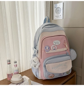 Detail of multi-pocket school backpack featuring transparent badge layer and cute plush charms