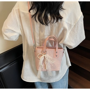 Detailaufnahme der rosa strukturierten Beuteltasche mit Spitzenschleife und Perlen