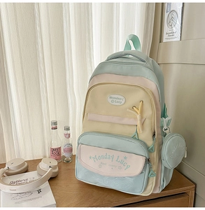 Close-up of a pastel student backpack featuring a small round coin pouch attachment