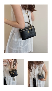 Close-up of black ostrich texture box bag with gold metal handle and chain strap