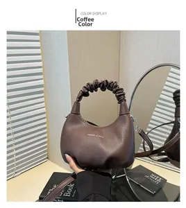 Detail of coffee brown pleated scrunchie handle on textured leather crossbody bag