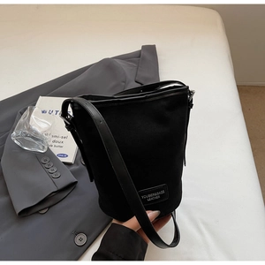 Detail der schwarzen mattierten Beuteltasche mit Leder-Logo-Etikett und Stoffstruktur