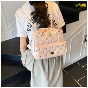 Detail of pink quilted backpack with silver star badge and rhinestone studs shown on model