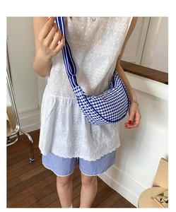 Detail of blue plaid crescent bag with wide striped shoulder strap and canvas texture