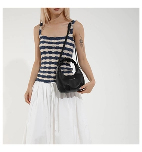 Close-up of black hobo bag with pleated handle and removable shoulder strap detail