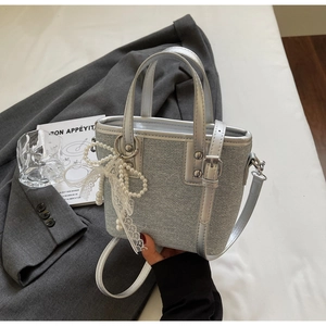 Details einer silbernen Beuteltasche mit Perlenspitze und glitzernder Denim-Textur