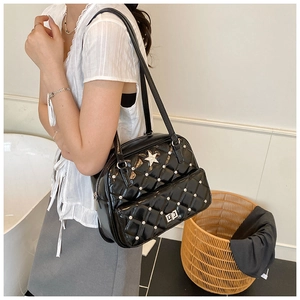 Close-up of black quilted shoulder bag with silver star charm and metallic turn-lock