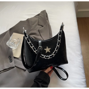 Détail du sac bandoulière en cuir verni noir avec logo étoile et chaîne argentée