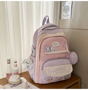 Detail view of pink and purple school backpack with cute rabbit pins and plush pendant