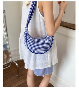 Detail view of blue and white gingham dumpling bag worn as a stylish crossbody bag