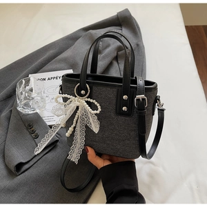 Detail der grauen Tweed-Beuteltasche mit Perlenspitzen-Schleife und Ledergriffen