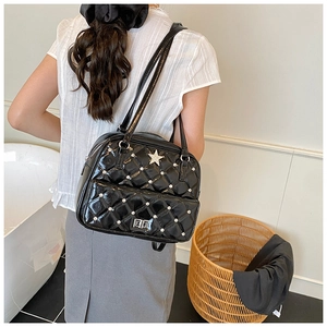 Detail of black quilted shoulder bag with silver star logo and diamond rivets on model