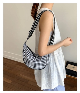 Detail of checkered dumpling bag with striped strap and crescent shape for styling
