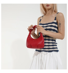 Detail of red lychee grain leather handbag with stylish pleated cloud handle and gold text