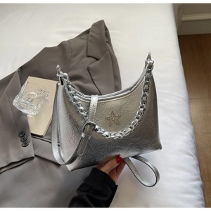 Détail d'un sac bandoulière argenté métallisé avec étoile en strass et chaîne élégante