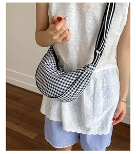 Detail of checkered dumpling bag with wide striped strap worn with a casual outfit