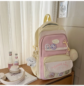 Detail of pink and yellow school backpack with cute badges and plush dog charm