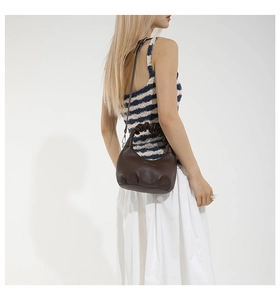 Close-up of a dark brown pleated dumpling bag with leather texture and brand lettering