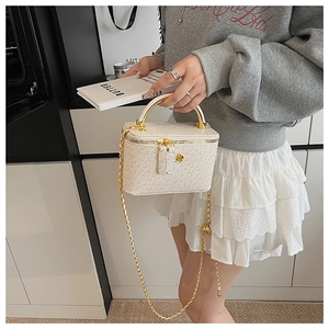 Detailed view of a white vanity bag with golden floral zipper and metallic handle