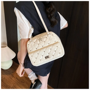 Detail of cream quilted shoulder bag with metal stars and studded silver rivets