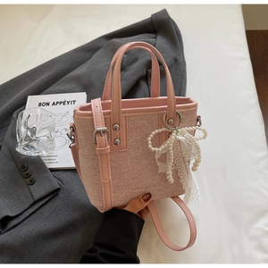 Detail der rosa gewebten Beuteltasche mit Perlen-Schleifen-Anhänger und Logo