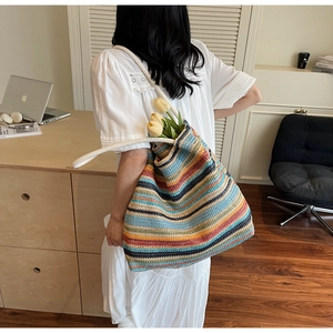Détail d'un grand sac cabas en paille à rayures avec des anses en corde pour les vacances