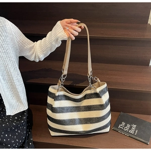 Detail of contrast woven tote bag with striped texture, leather handle and chain links