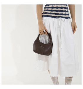 Detail of dark brown crescent handbag with lychee texture and pleated handle design