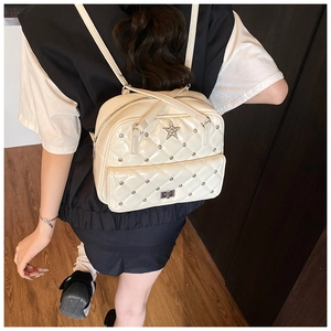 Detail of cream quilted backpack with silver star emblem and studs on model