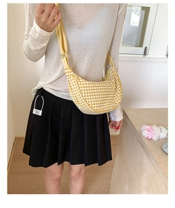 Detailed close-up of yellow and white checkered half-moon bag with striped wide shoulder strap